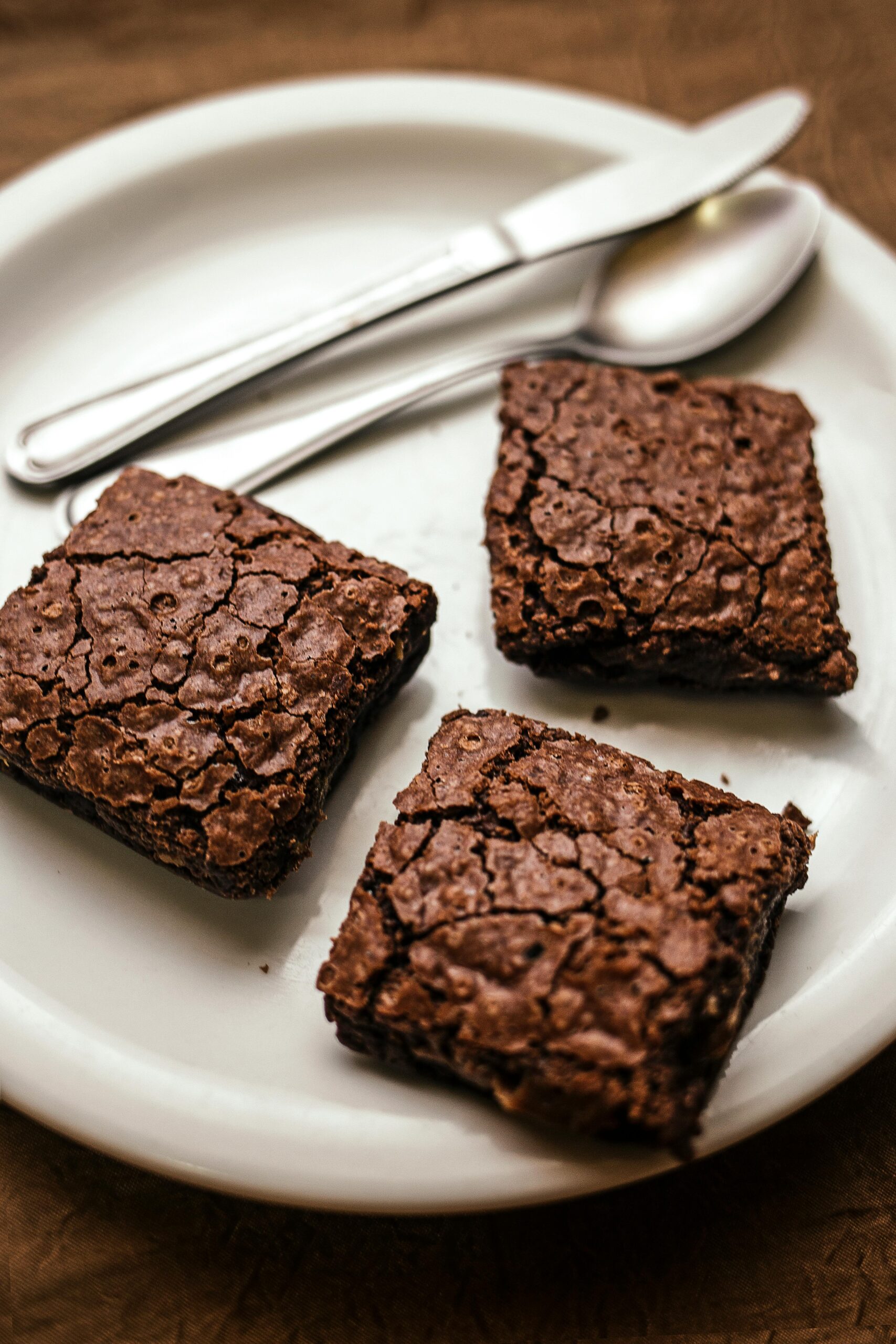 easy homemade brownies recipe.Rich chocolate fudge brownies served on a plate with chocolate sauce drizzle, perfect for a quick eggless dessert recipe