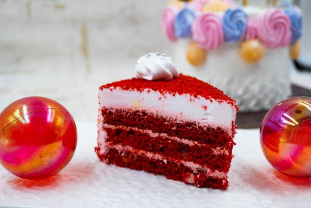 Slice of red velvet cake recipe showing moist layers with cream frosting