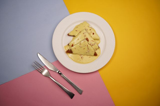 Slices of rich besan gram flour halwa served on a white plate with a fork and knife, perfect as a quick Eid dessert recipe under 30 minutes.