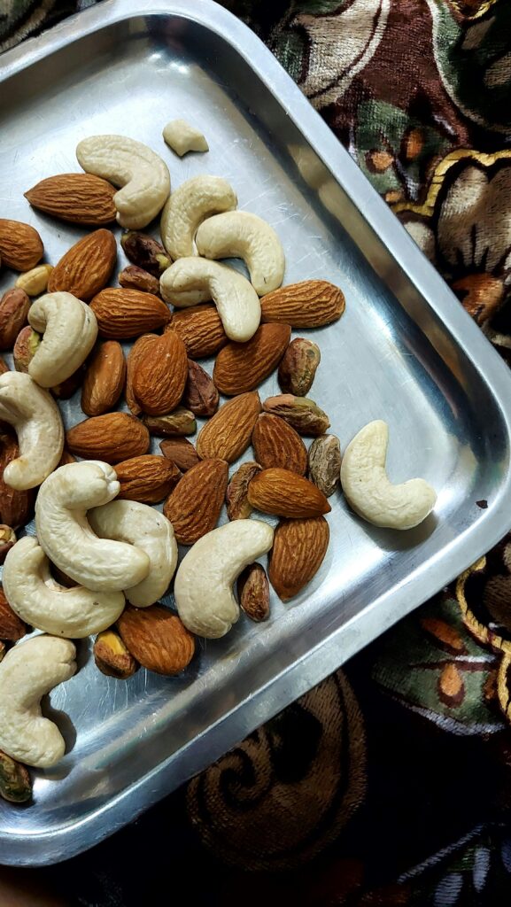A mix of raw almonds and cashew nuts on a silver tray for traditional Eid desserts