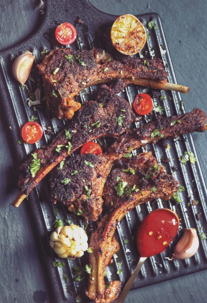 picy grilled lamb chops garnished with fresh coriander and sliced tomatoes