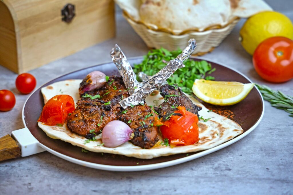 Pakistani style oven baked mutton leg roast served with fresh naan and lemon wedges