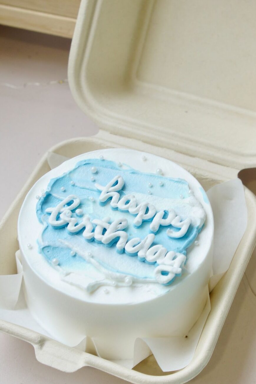 A light blue and white Korean aesthetic minimalist bento cake for beginners packed neatly in a styrofoam lunch box.