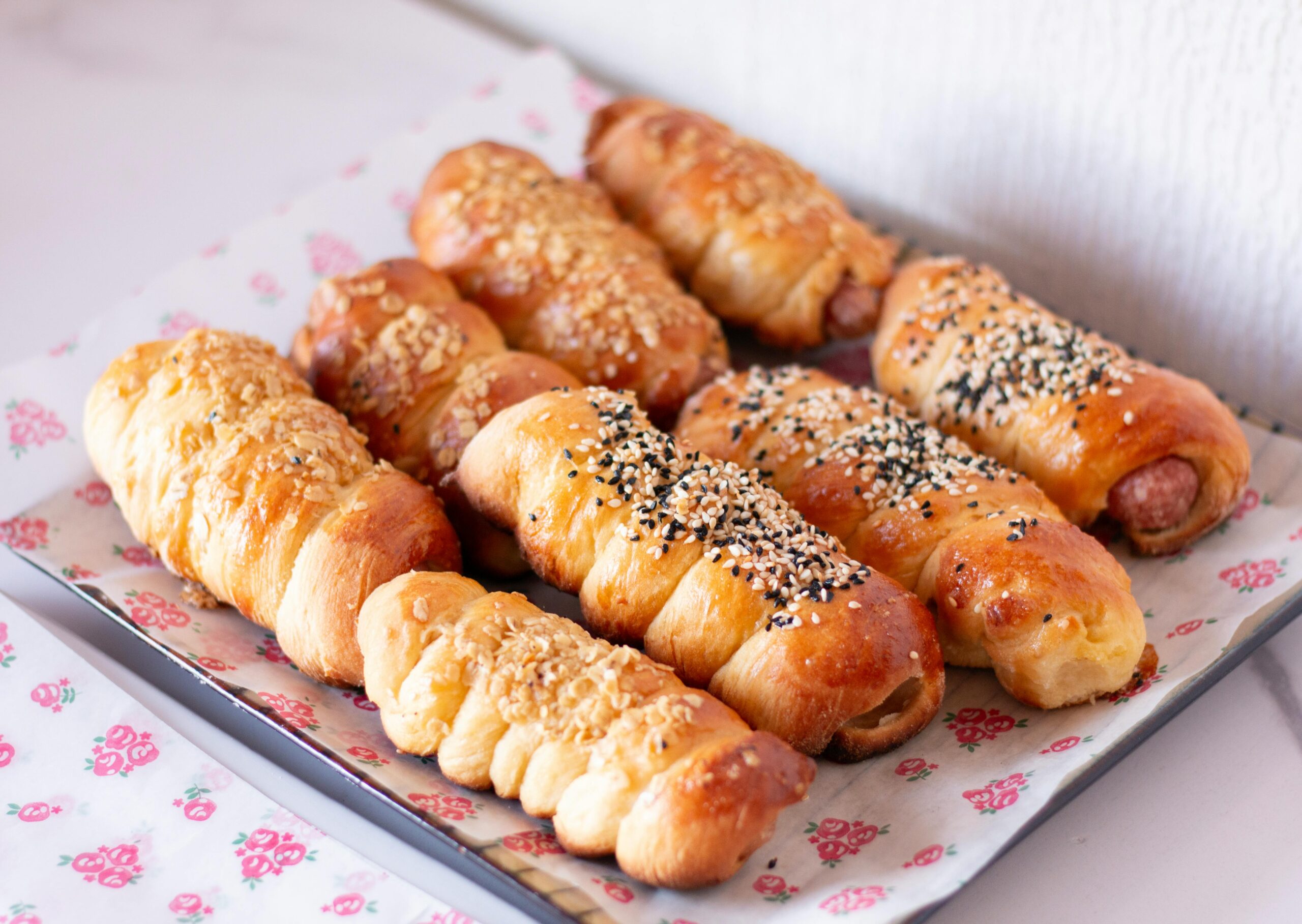Golden brown Air Fryer Sausage Rolls with sesame seeds served on a tray for Father's Day brunch. Yeh tray mein rakhe hue crispy, sunehri rolls hain jinki topping par sesame seeds (til) ya spices lage hain.