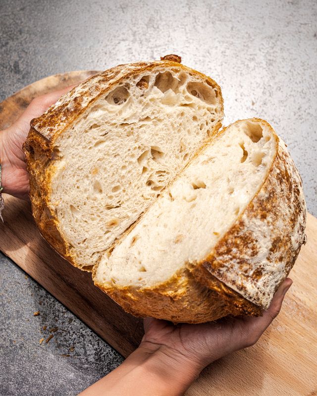 Hand holding a sliced open crumb easy sourdough garlic bread loaf

