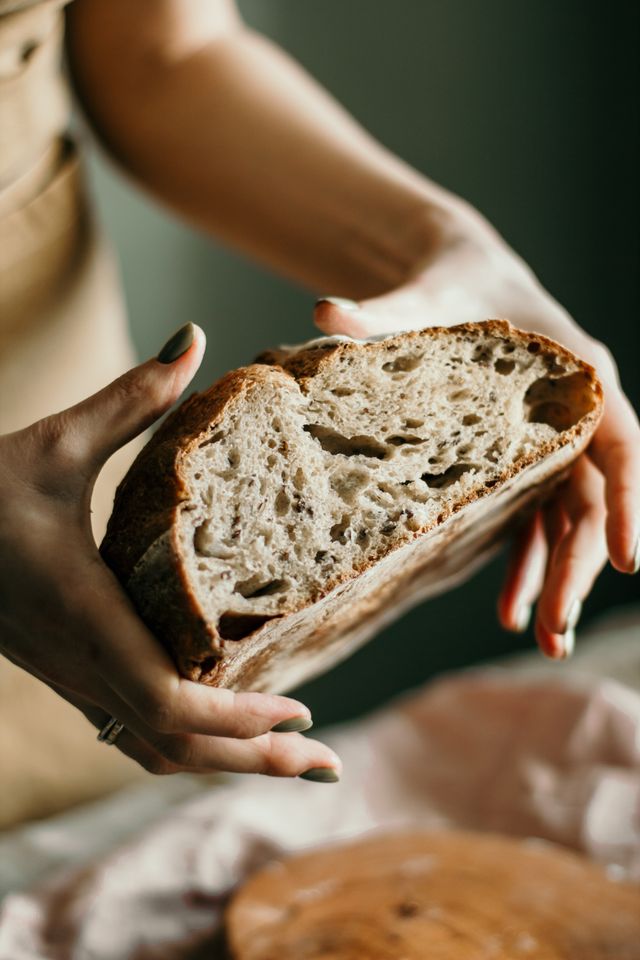 Hand holding a torn piece of cardamom sourdough bread revealing soft crumb texture